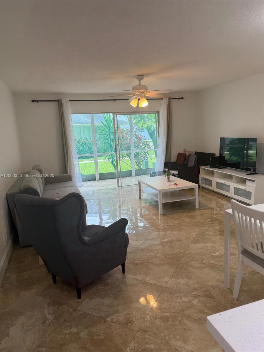 A living room features tile floors, a ceiling fan, and sliding doors to a patio — 219 NE 14th Ave # 101, Hallandale Beach FL 33009, HALLANDALE BEACH, FL