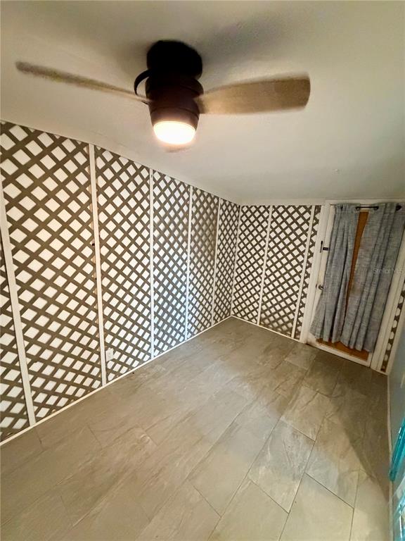 A room with light-colored tile flooring, a ceiling fan, and walls covered in white lattice — 3452 9TH AVENUE N UNIT Lower, ST PETERSBURG, FL