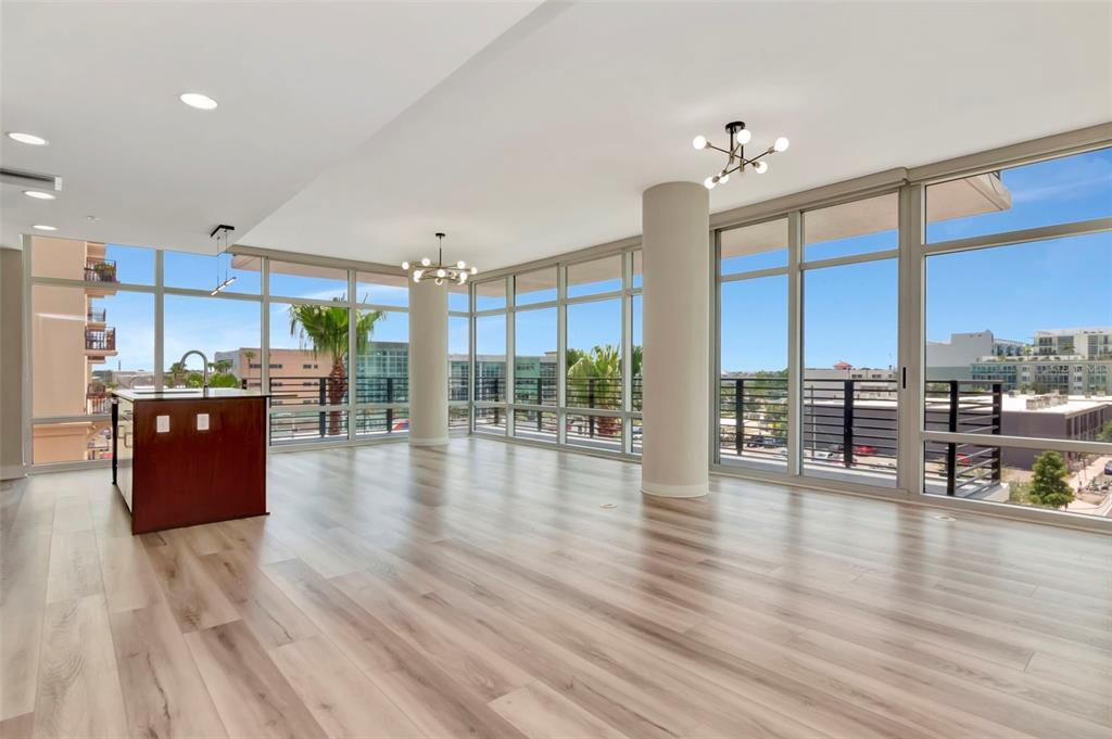 An open-concept living area features light wood flooring, floor-to-ceiling windows, and a kitchen island — 1208 E KENNEDY BOULEVARD UNIT 419, TAMPA, FL