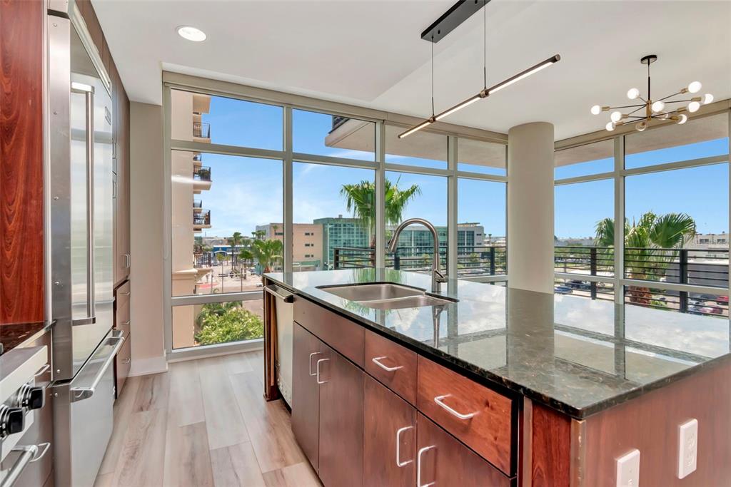 A modern kitchen features a dark granite island, stainless steel appliances, and floor-to-ceiling windows — 1208 E KENNEDY BOULEVARD UNIT 419, TAMPA, FL