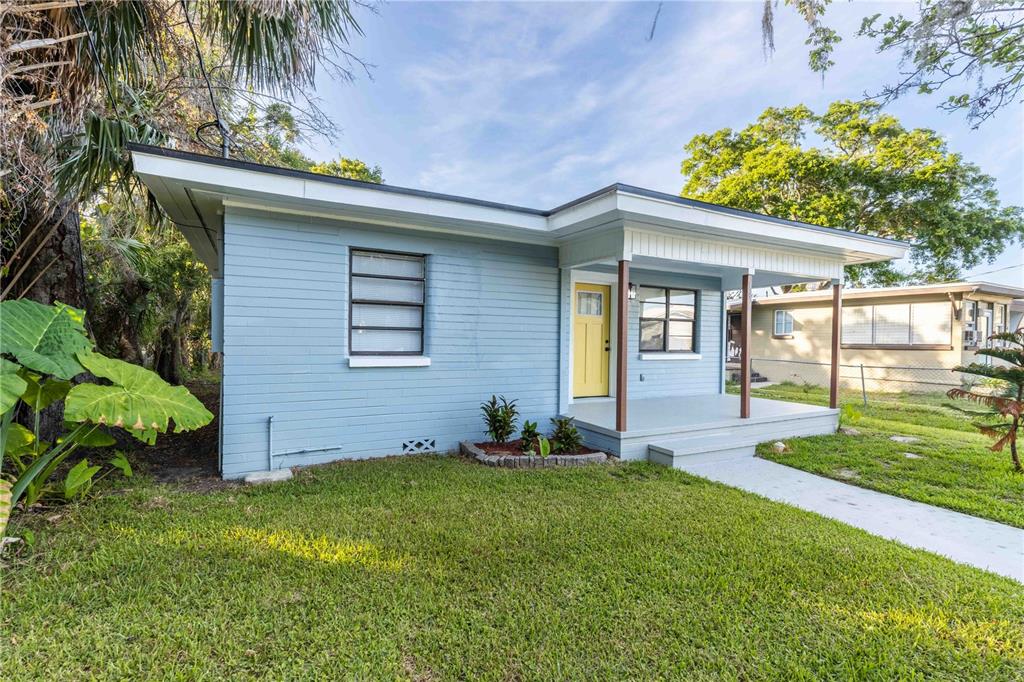 A light blue, single-story house with a yellow front door and a covered porch — 136 TAYLOR AVENUE, DAYTONA BEACH, FL
