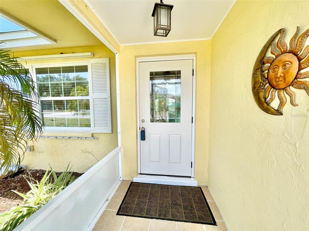 A white front door with a glass insert sits on a porch with yellow walls — 5240 DREW ROAD, VENICE, FL