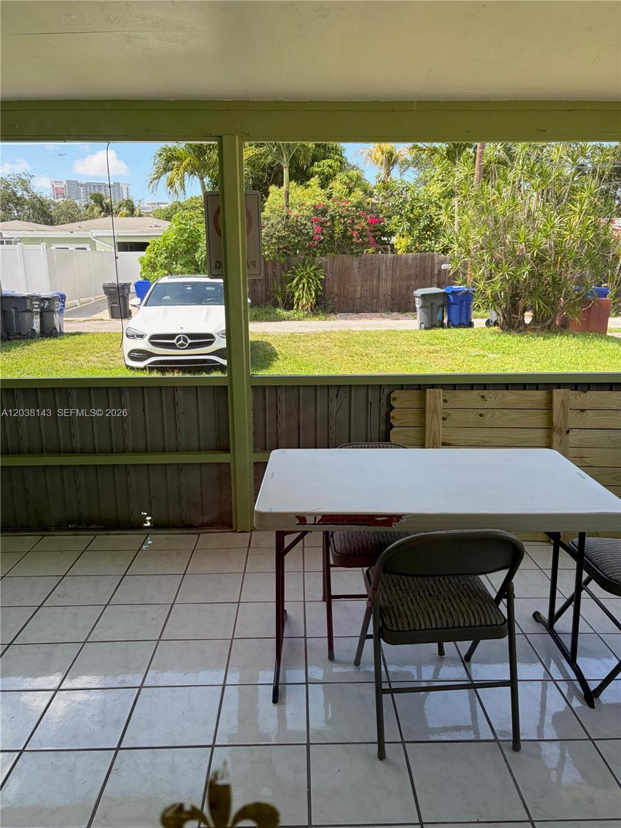 A tiled screened-in porch features a folding table and chairs overlooking a residential street — 1635 Dewey St # B, Hollywood FL 33020, HOLLYWOOD, FL