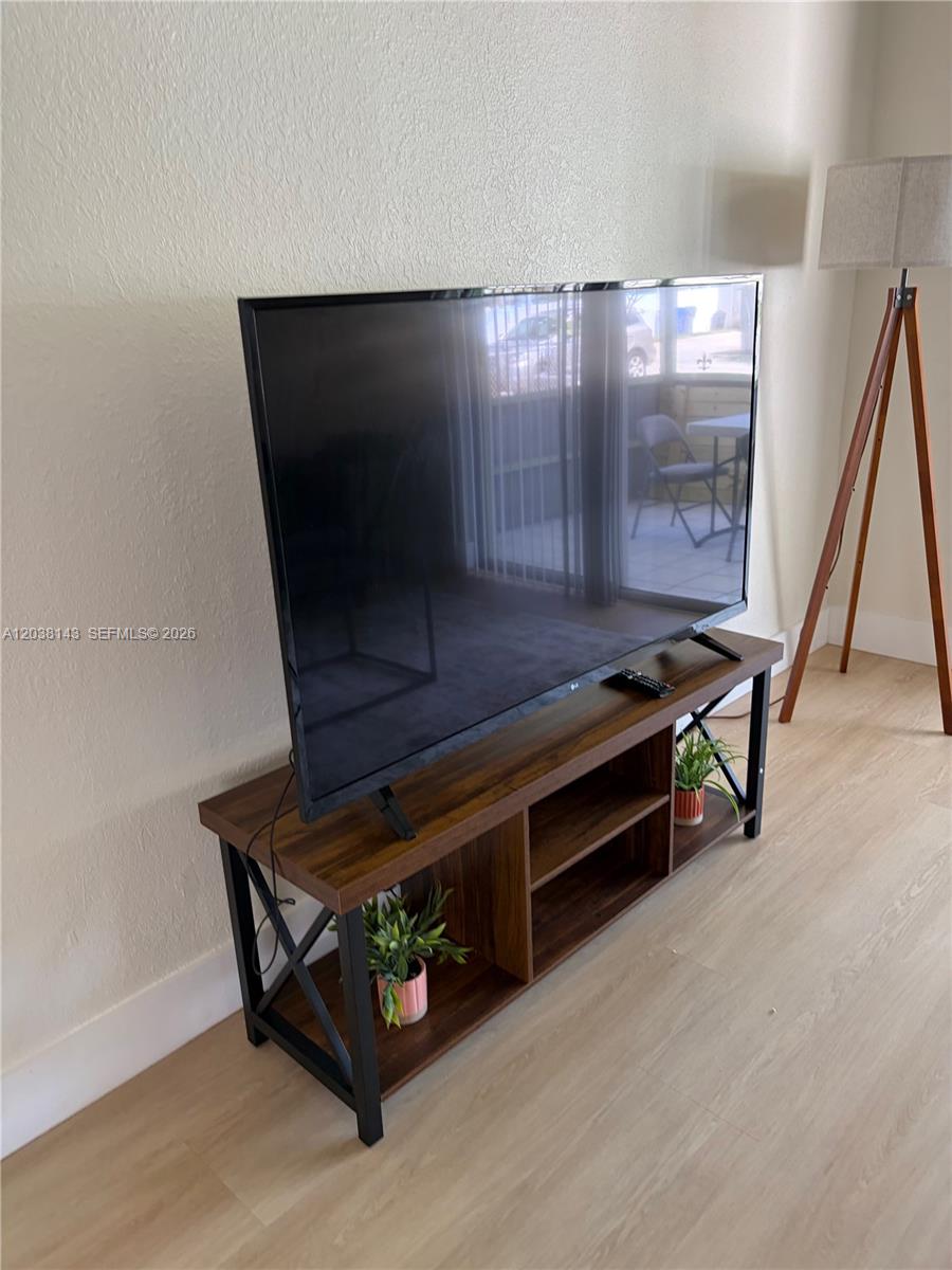 A television sits on a wooden media console with black metal legs in a room — 1635 Dewey St # B, Hollywood FL 33020, HOLLYWOOD, FL