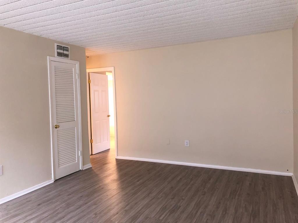An empty room with light-colored walls, wood-look flooring, and a white louvered closet door — 1311 BAYWATCH LOOP UNIT 204, TAMPA, FL