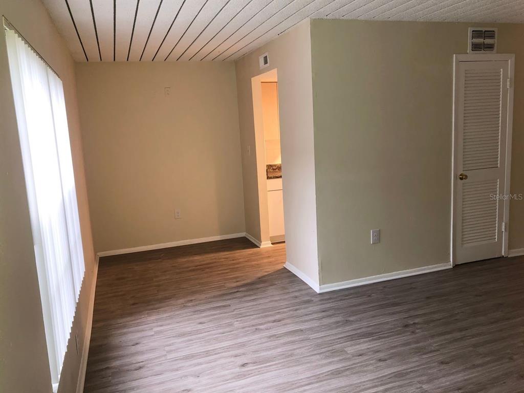 An interior view shows a room with wood-look flooring, beige walls, and a louvered door — 1311 BAYWATCH LOOP UNIT 204, TAMPA, FL