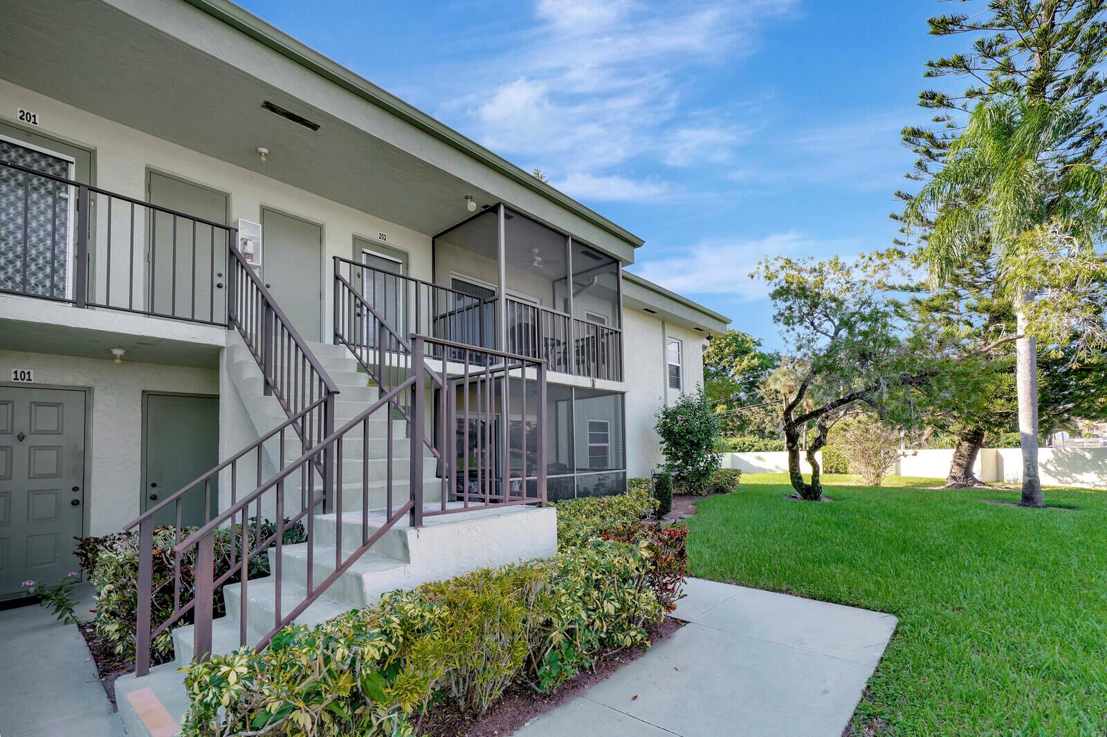 Exterior view of a two-story apartment building with a staircase leading to second-floor units — 7547 S Oriole Boulevard # 202, Delray Beach FL 33446, DELRAY BEACH, FL