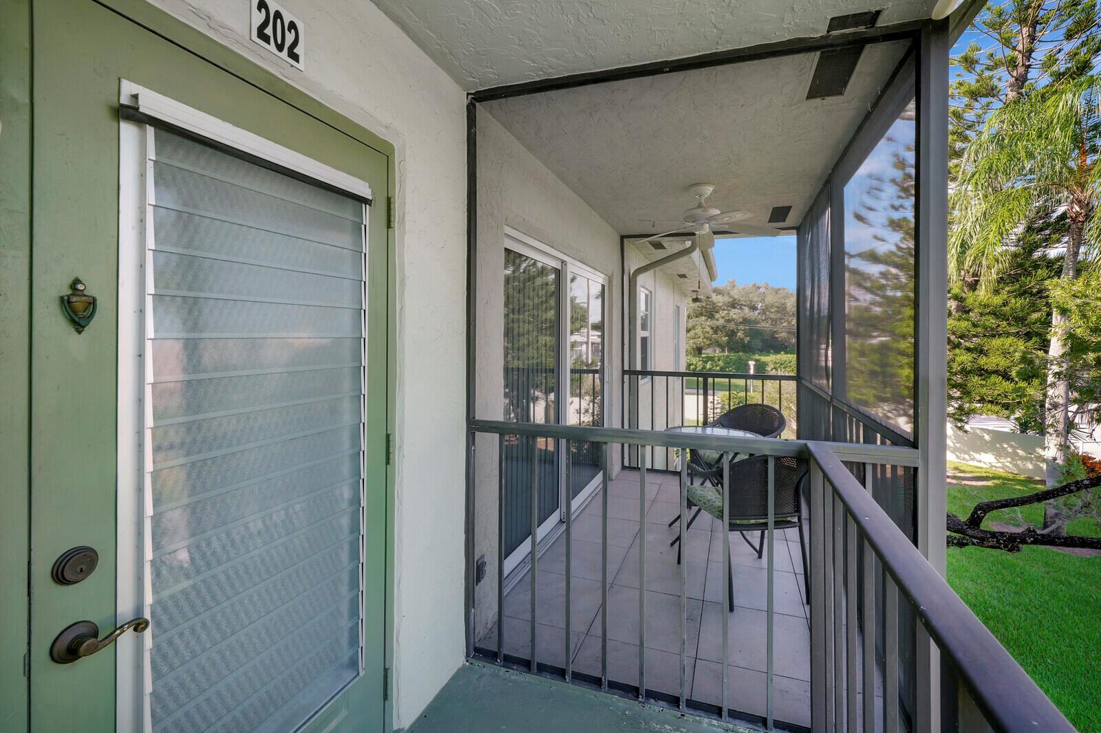 A screened-in balcony with tile flooring, a ceiling fan, and a small bistro set — 7547 S Oriole Boulevard # 202, Delray Beach FL 33446, DELRAY BEACH, FL