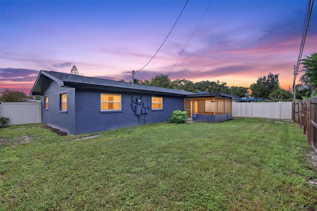 The exterior of a blue single-story house with a screened-in porch and a fenced backyard — 1748 GREENLEA DRIVE, CLEARWATER, FL