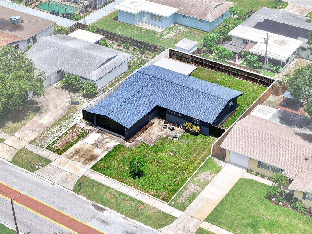 An aerial view shows a dark-colored L-shaped house with a blue roof and a driveway — 1748 GREENLEA DRIVE, CLEARWATER, FL