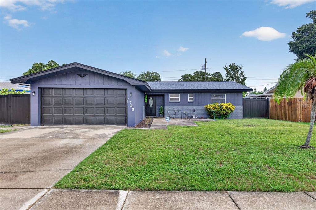 A single-story house with a dark blue exterior, a two-car garage, and a front lawn — 1748 GREENLEA DRIVE, CLEARWATER, FL