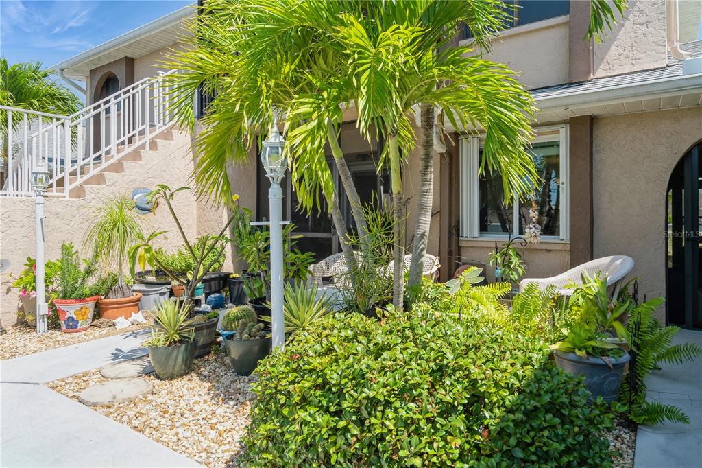 A patio area features a palm tree, potted plants, and a white metal staircase — 527 CAPE CORAL PARKWAY W UNIT 4, CAPE CORAL, FL