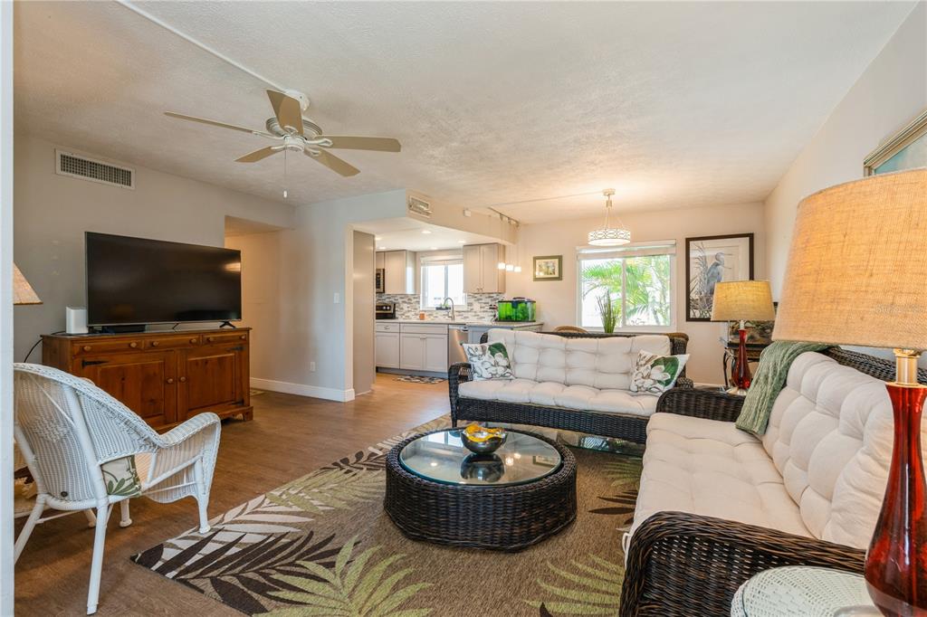 A living room with wicker furniture, a glass coffee table, and an open kitchen area — 527 CAPE CORAL PARKWAY W UNIT 4, CAPE CORAL, FL