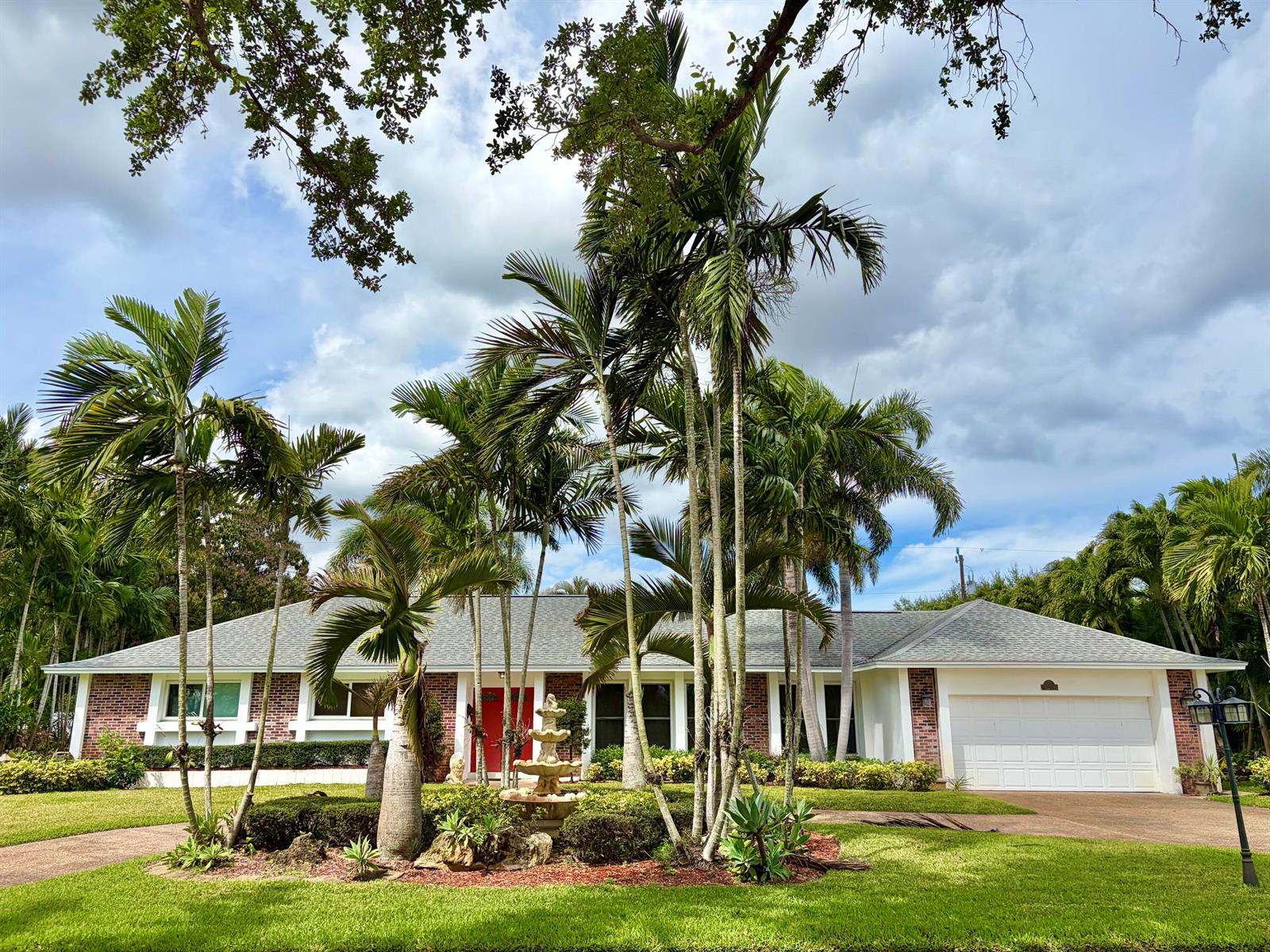 A single-story brick house with a white garage and palm trees in the front yard — 8 Bell Lane, Palm Springs FL 33406, PALM SPRINGS, FL