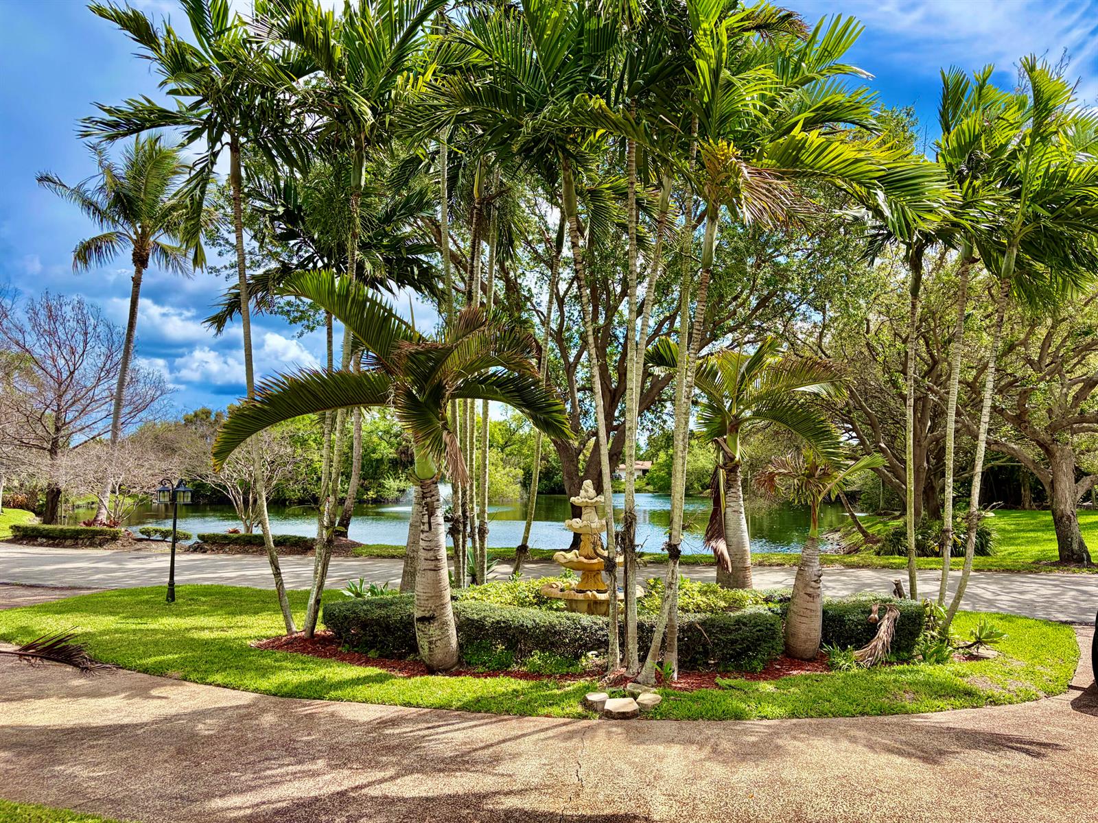 A circular garden with palm trees and a tiered fountain overlooks a lake — 8 Bell Lane, Palm Springs FL 33406, PALM SPRINGS, FL