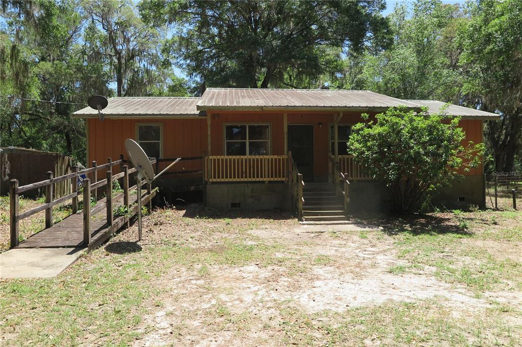 A single-story orange house with a metal roof, a front porch, and a wooden ramp — 153 RANCH ROAD, EAST PALATKA, FL
