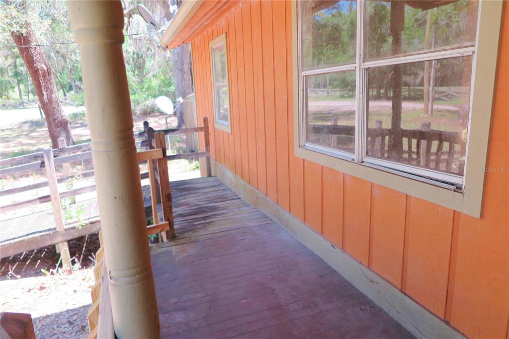 A wooden porch with a railing runs along the side of an orange-sided house — 153 RANCH ROAD, EAST PALATKA, FL