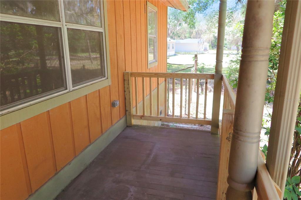 A wooden porch features a railing, a support post, and orange vertical siding — 153 RANCH ROAD, EAST PALATKA, FL