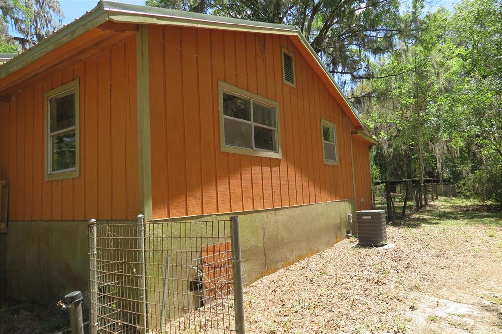 The exterior of an orange house features vertical wood siding and a concrete foundation — 153 RANCH ROAD, EAST PALATKA, FL