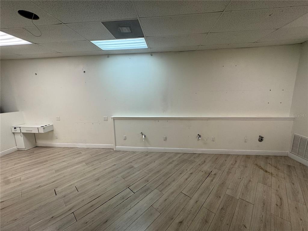 An empty commercial room features light wood-look flooring, white walls, and a drop ceiling — 3274 COMMERCIAL WAY, SPRING HILL, FL