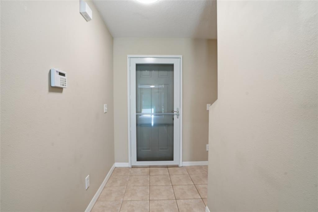 An entryway features beige walls, a tiled floor, and a white storm door — 4610 WINDING RIVER WAY, LAND O LAKES, FL