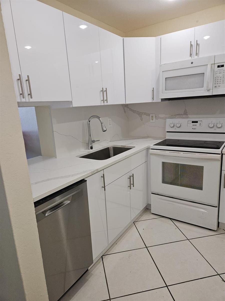 A kitchen features white glossy cabinets, stainless steel appliances, and white marble-patterned countertops — 5665 W 20th Avenue # 413, Hialeah FL 33012, HIALEAH, FL