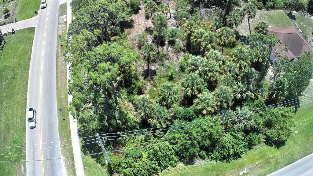 An aerial view shows a wooded, undeveloped lot situated between two paved roads — Lot #11 N CHAMBERLAIN BOULEVARD, NORTH PORT, FL