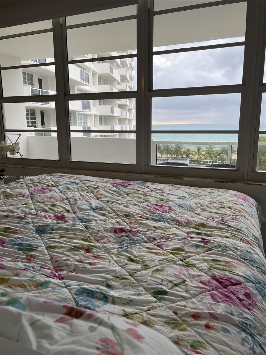 A bedroom features a floral-patterned bedspread and a large window overlooking the ocean — 100 Lincoln Rd # 719, Miami Beach FL 33139, MIAMI BEACH, FL