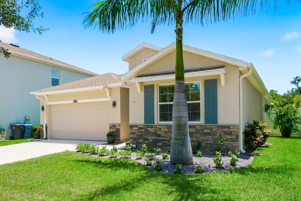 A single-story house with a beige stucco exterior, stone accents, and a palm tree — 8216 PRAISE DRIVE, TAMPA, FL