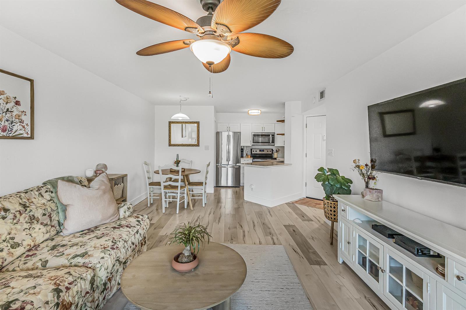 A living room and dining area feature wood-look flooring, a ceiling fan, and white cabinetry — 1850 Charlesmont Drive # 119, Indialantic FL 32903, INDIALANTIC, FL
