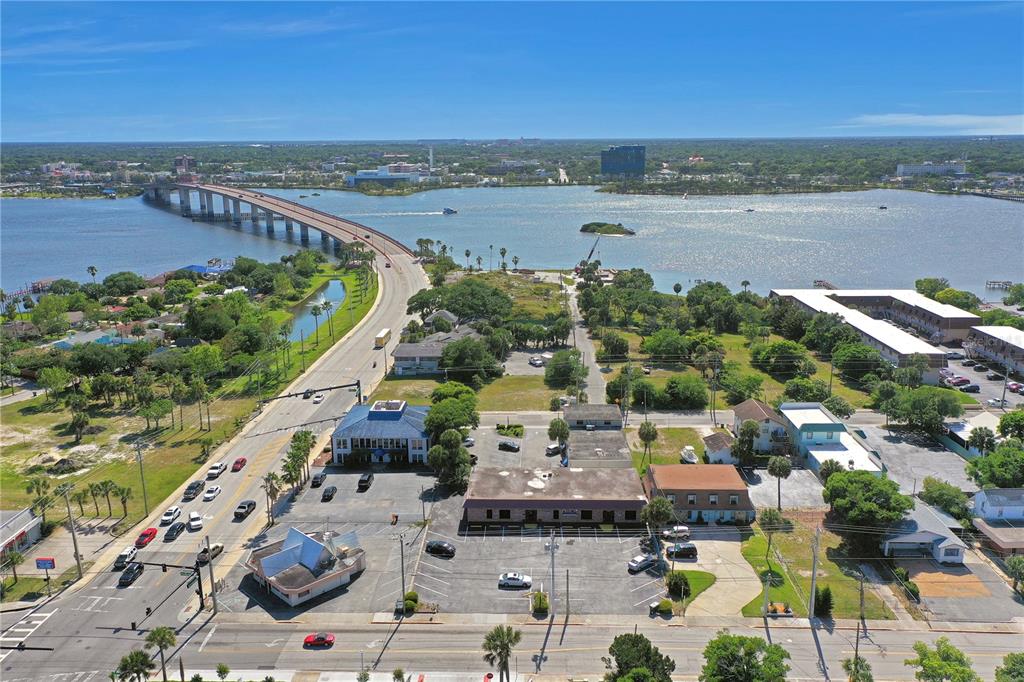 An aerial view shows a bridge over a body of water near commercial buildings — 162 S PENINSULA DRIVE, DAYTONA BEACH, FL