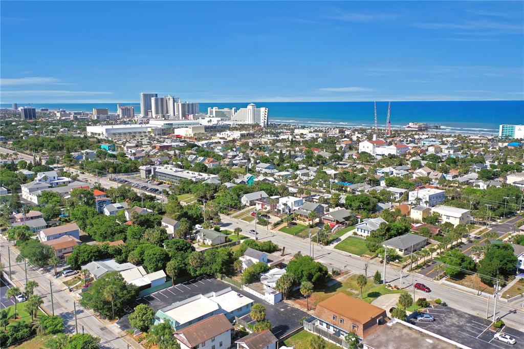 An aerial view shows a coastal town with houses, streets, and a beach in the distance — 162 S PENINSULA DRIVE, DAYTONA BEACH, FL
