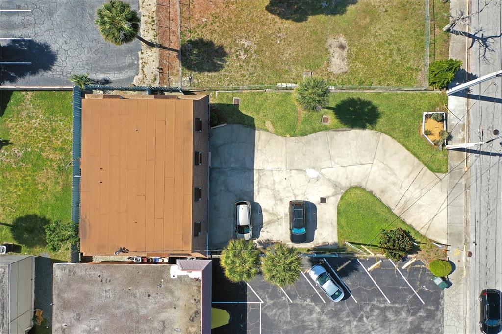 An aerial view shows a building with a brown roof, a concrete parking area, and landscaping — 162 S PENINSULA DRIVE, DAYTONA BEACH, FL