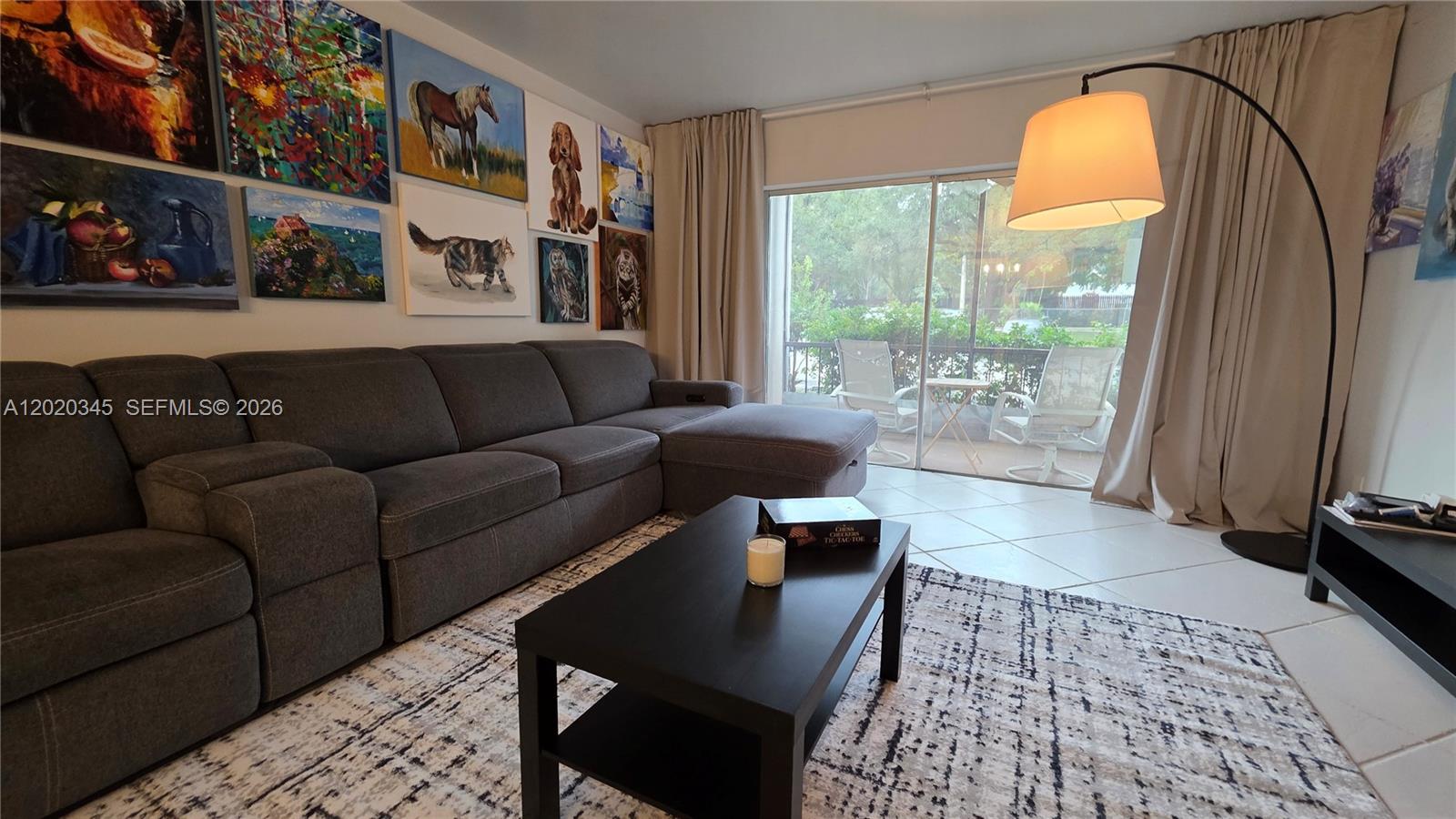 A living room features a gray sectional sofa, a coffee table, and a gallery wall — 3360 Spanish Moss Ter # 104, Lauderhill FL 33319, LAUDERHILL, FL