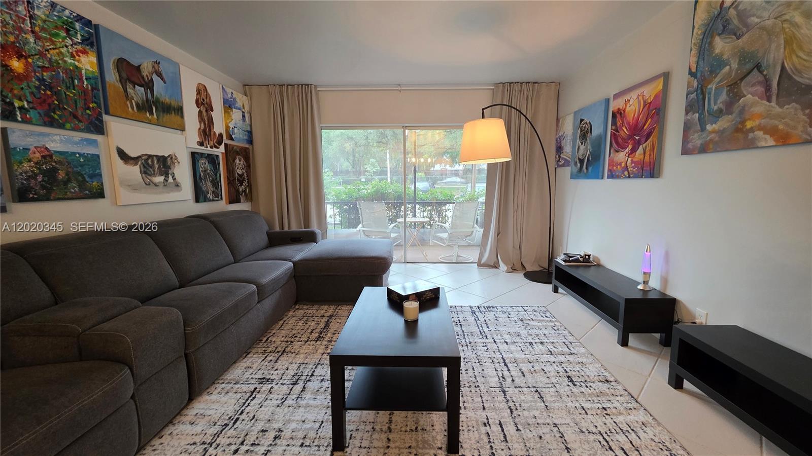 A living room features a gray sectional sofa, a coffee table, and multiple wall paintings — 3360 Spanish Moss Ter # 104, Lauderhill FL 33319, LAUDERHILL, FL