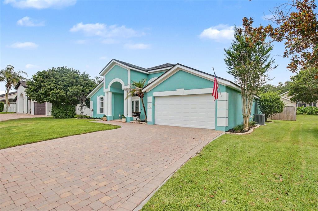A teal single-story house with a white garage and a paved driveway under a blue sky — 1986 CRYSTAL DOWNS COURT, OVIEDO, FL