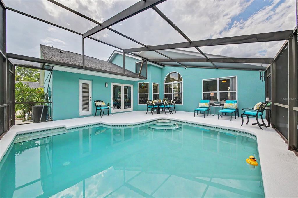 A screened-in swimming pool patio features turquoise exterior walls and outdoor furniture — 1986 CRYSTAL DOWNS COURT, OVIEDO, FL