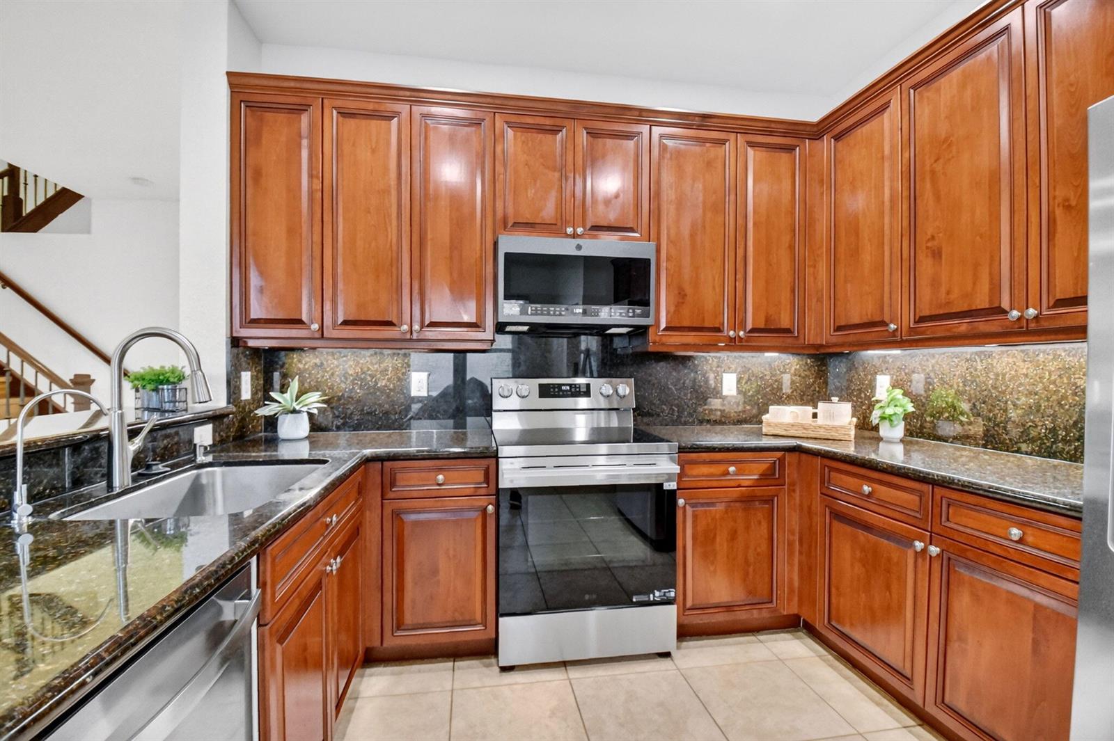 A kitchen features cherry wood cabinets, stainless steel appliances, and dark granite countertops — 7662 Spatterdock Drive, Boynton Beach FL 33437, BOYNTON BEACH, FL