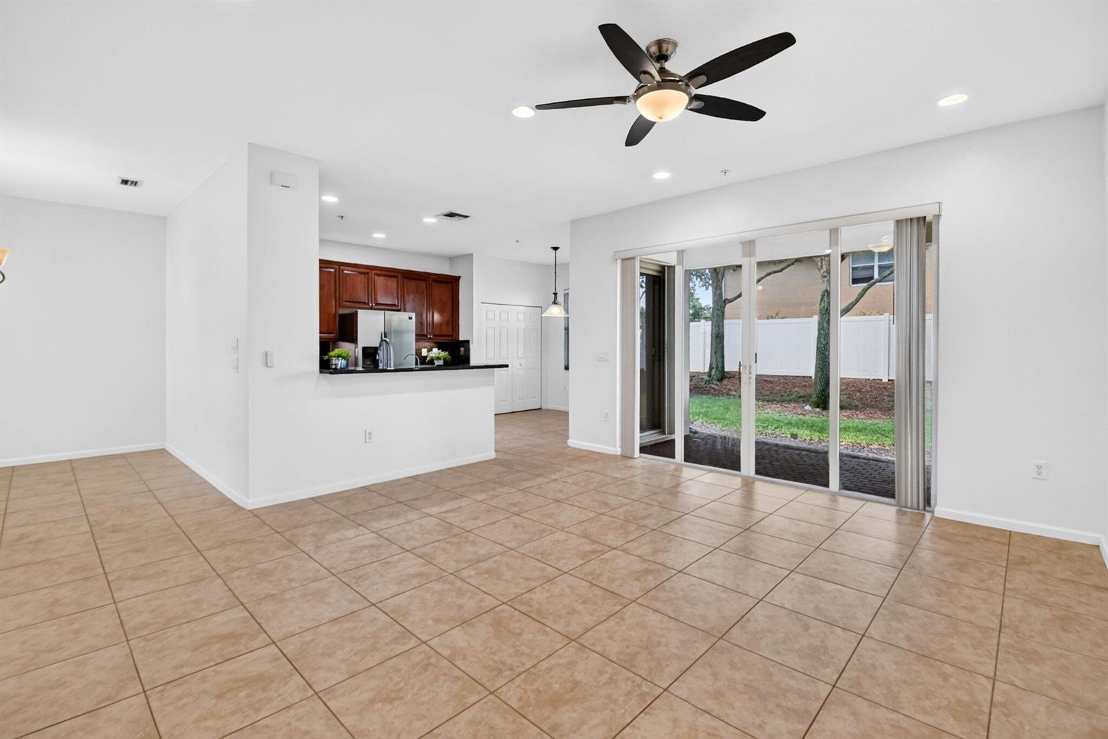 An open-concept living area with tile flooring, a ceiling fan, and sliding glass patio doors — 7662 Spatterdock Drive, Boynton Beach FL 33437, BOYNTON BEACH, FL