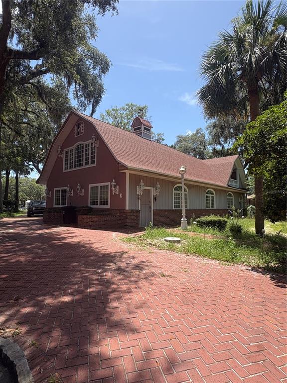 A two-story barn-style building with a brick driveway and exterior brick and siding — 976 SW HAMLET CIRCLE UNIT E, LAKE CITY, FL