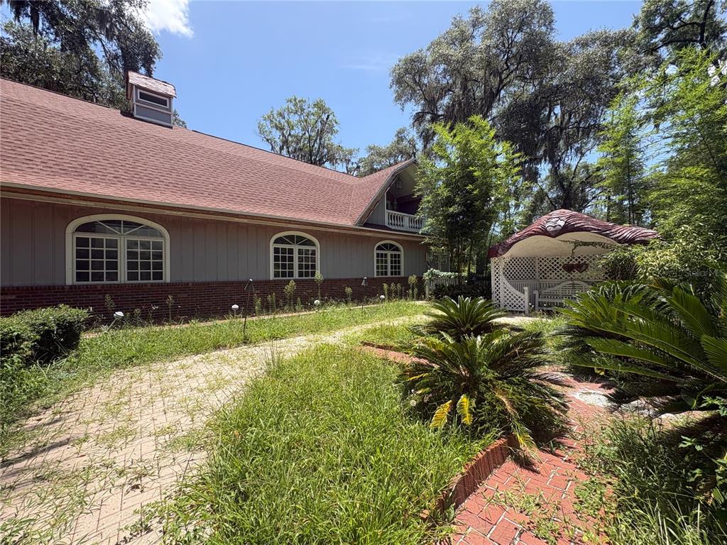 A side view of a house with a brick base, siding, and a nearby gazebo — 976 SW HAMLET CIRCLE UNIT E, LAKE CITY, FL