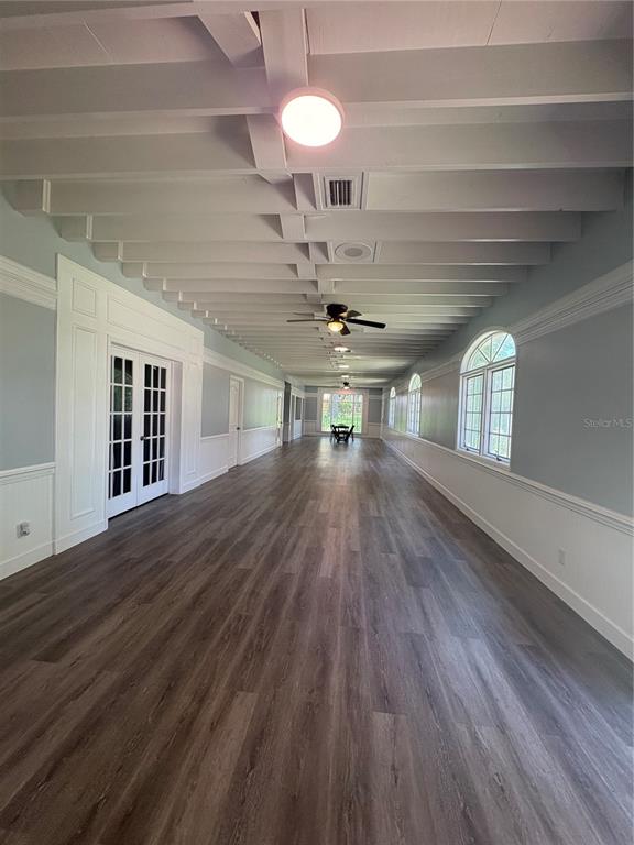 A long, narrow room features a beamed ceiling, wood-look flooring, and multiple arched windows — 976 SW HAMLET CIRCLE UNIT E, LAKE CITY, FL