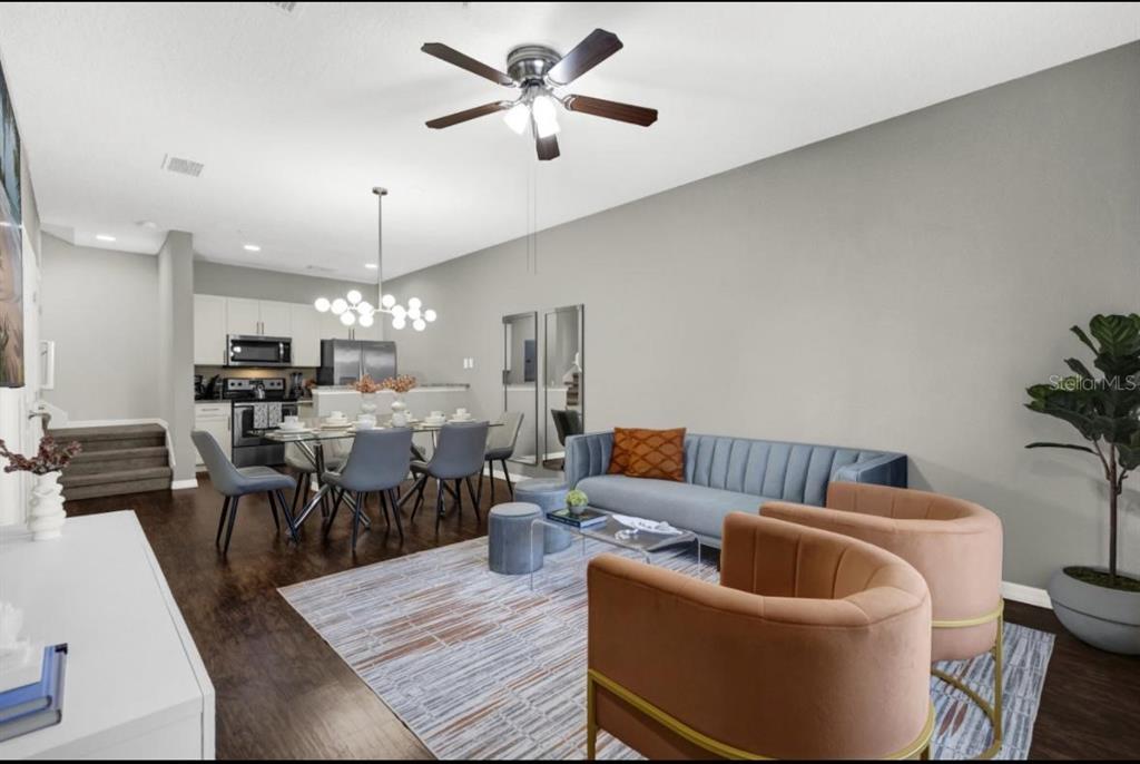 An open-concept living and dining area features a blue sofa, two peach chairs, and hardwood floors — 3202 GUANA WAY, KISSIMMEE, FL