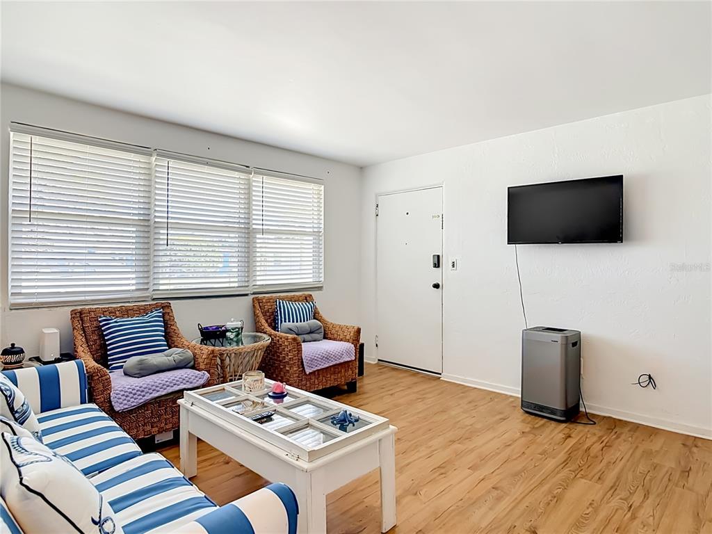 A living room features light wood flooring, wicker chairs, a striped sofa, and a wall-mounted television — 27 ALAMANDA DRIVE, ORMOND BEACH, FL
