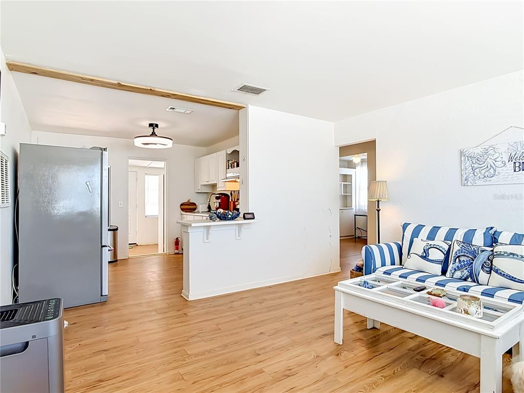 A living room with light wood floors features a blue-striped sofa and a kitchen pass-through — 27 ALAMANDA DRIVE, ORMOND BEACH, FL
