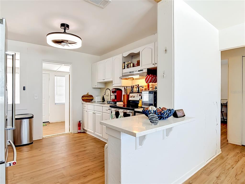 A kitchen with white cabinets, light wood flooring, and a breakfast bar peninsula — 27 ALAMANDA DRIVE, ORMOND BEACH, FL