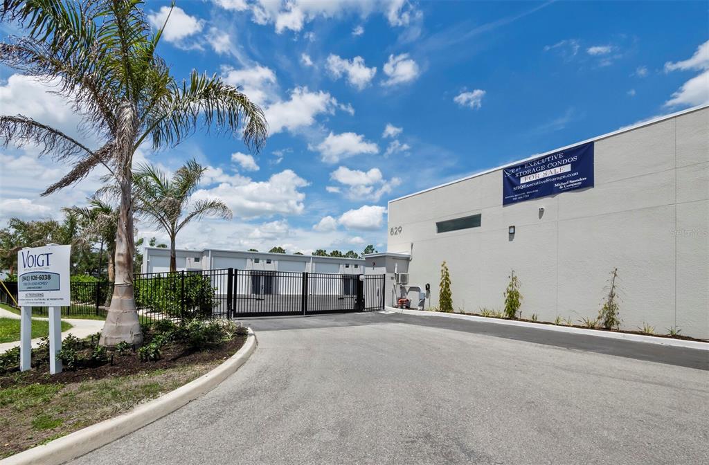 A gated entrance leads to a commercial storage condo complex with a palm tree — 829 57TH STREET E UNIT 28, BRADENTON, FL