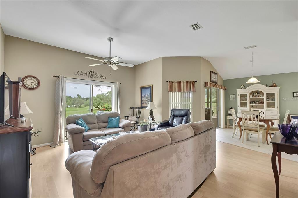 A living room and dining area with light wood floors, neutral walls, and sliding glass doors — 547 W HILLWOOD PATH, BEVERLY HILLS, FL