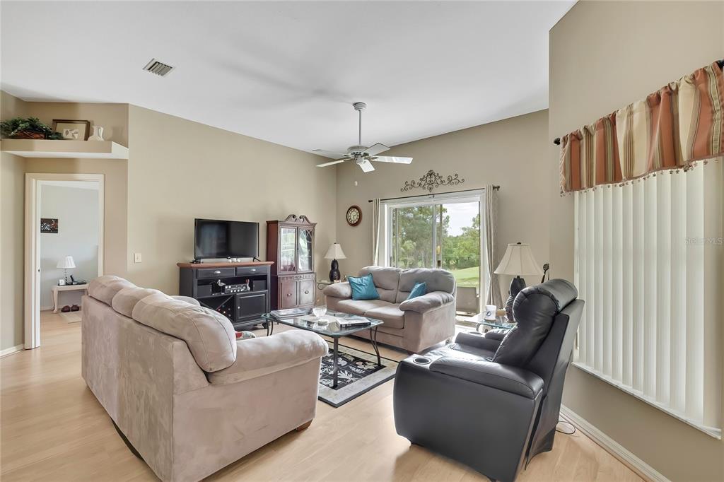 A living room features light wood flooring, beige walls, a ceiling fan, and sliding glass doors — 547 W HILLWOOD PATH, BEVERLY HILLS, FL