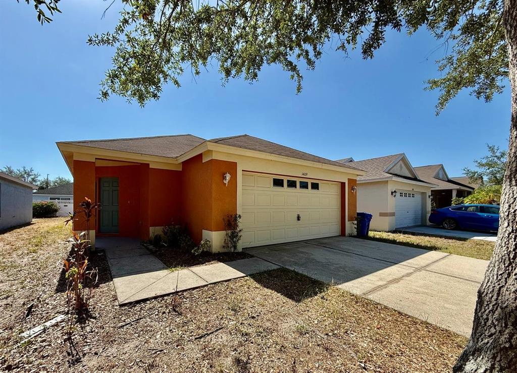 A single-story house with an orange exterior, a two-car garage, and a concrete driveway — 1409 DELANO TRENT STREET, RUSKIN, FL